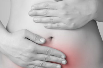A woman holding her abdomen which is shaded in red